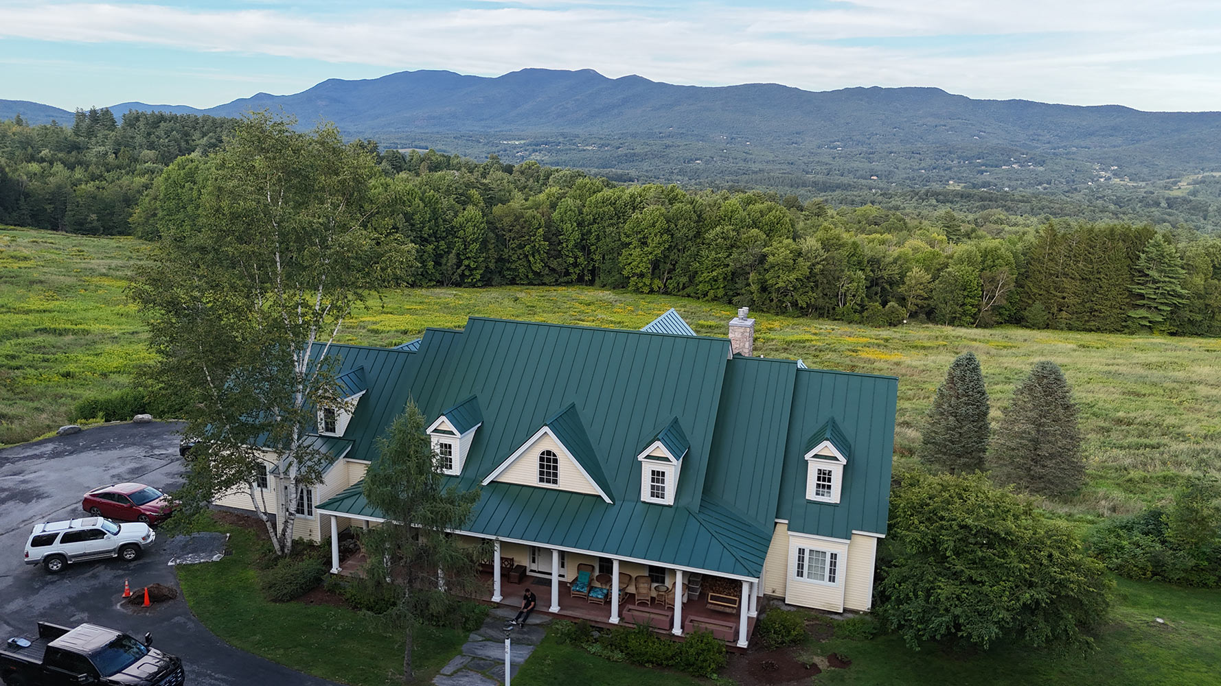 Standing seam metal roof Waterbury Vermont with Vermont Green Mountains backdrop aerial drone