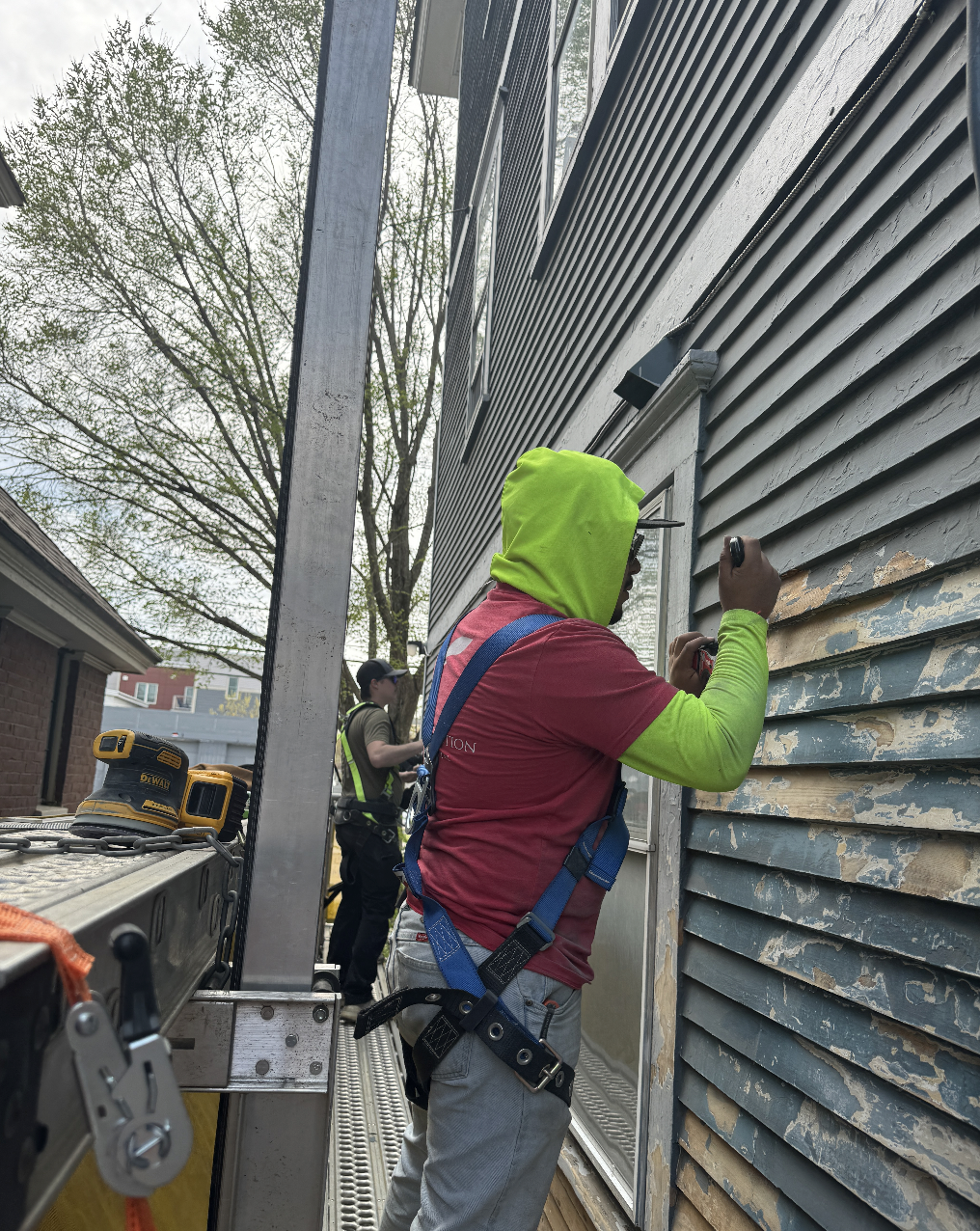 Exterior siding painting prep on scaffolding Vermont Rivers Construction