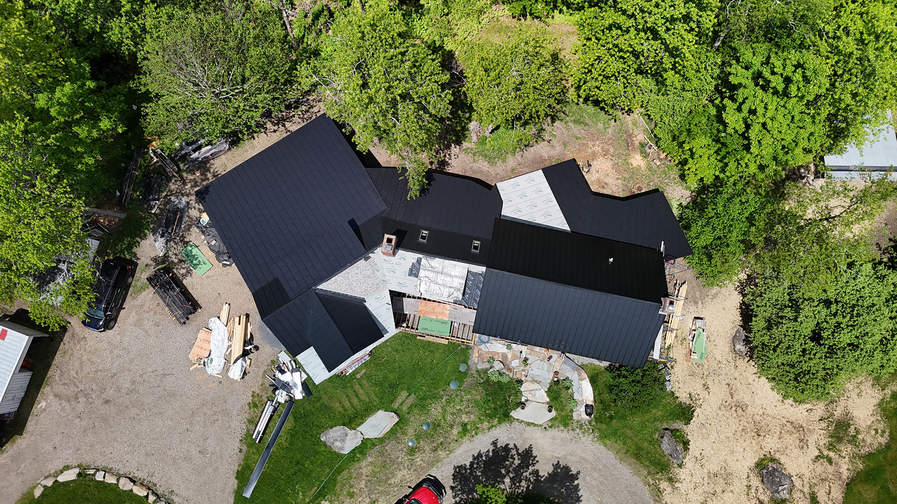 Matte black standing seam roof half-installed Lincoln Vermont aerial