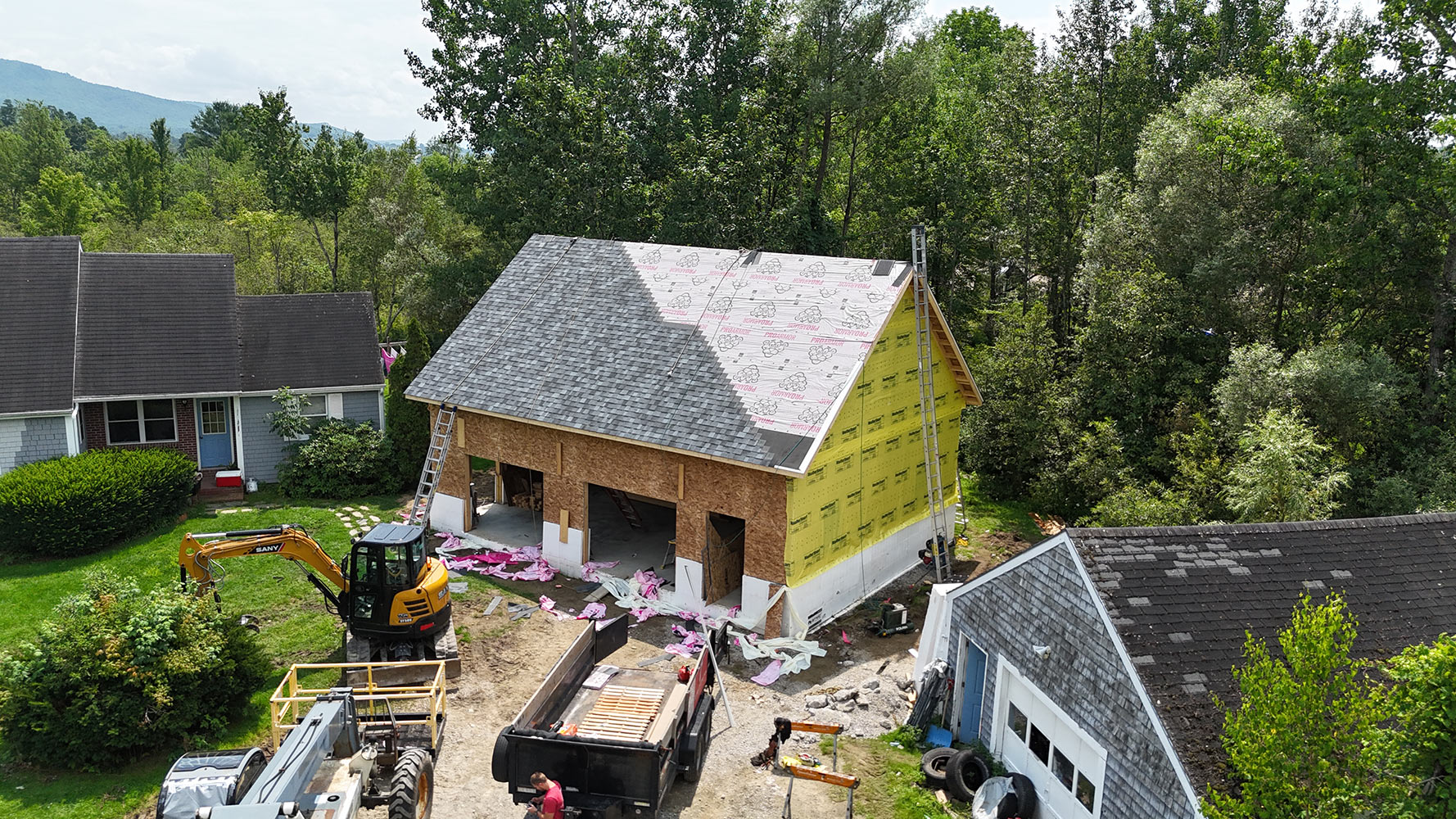 New construction build Hinesburg Vermont drone aerial — active site with excavator