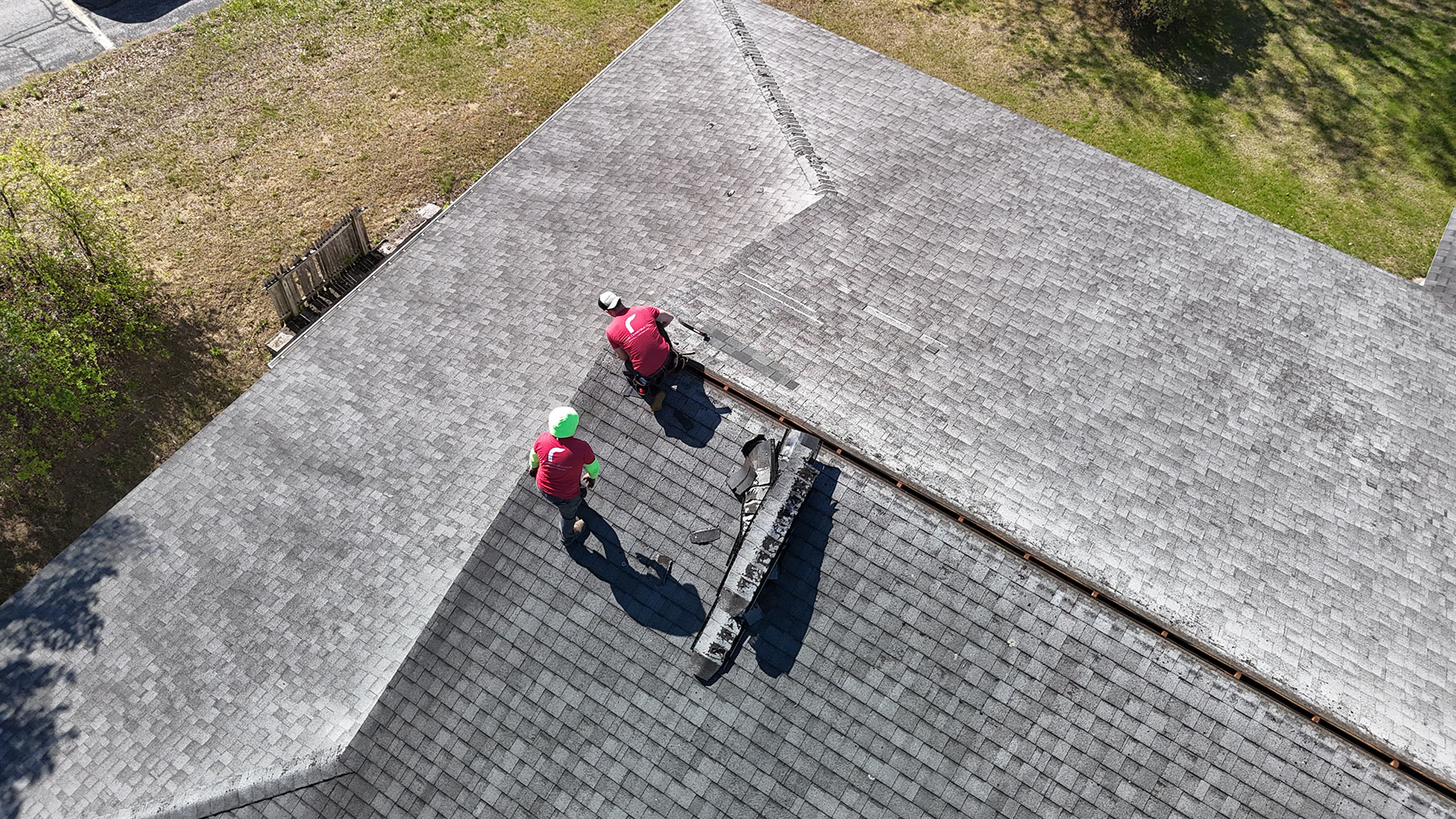 Overhead drone view of commercial roof repair in Essex Vermont showing Rivers Construction crew removing deteriorated ridge cap shingles