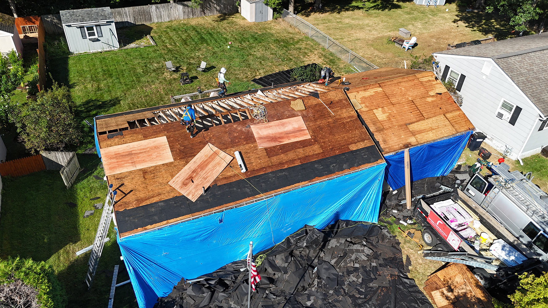 Tear-off phase — bare deck exposed with new plywood patches on residential roof in Burlington Vermont North End, Rivers Construction crew working
