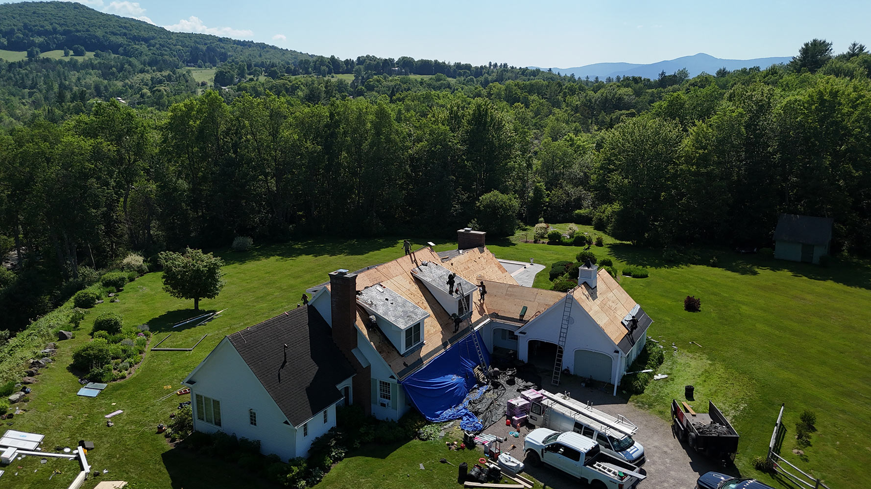 Crew installing shingle roof with Vermont mountain views Stowe aerial