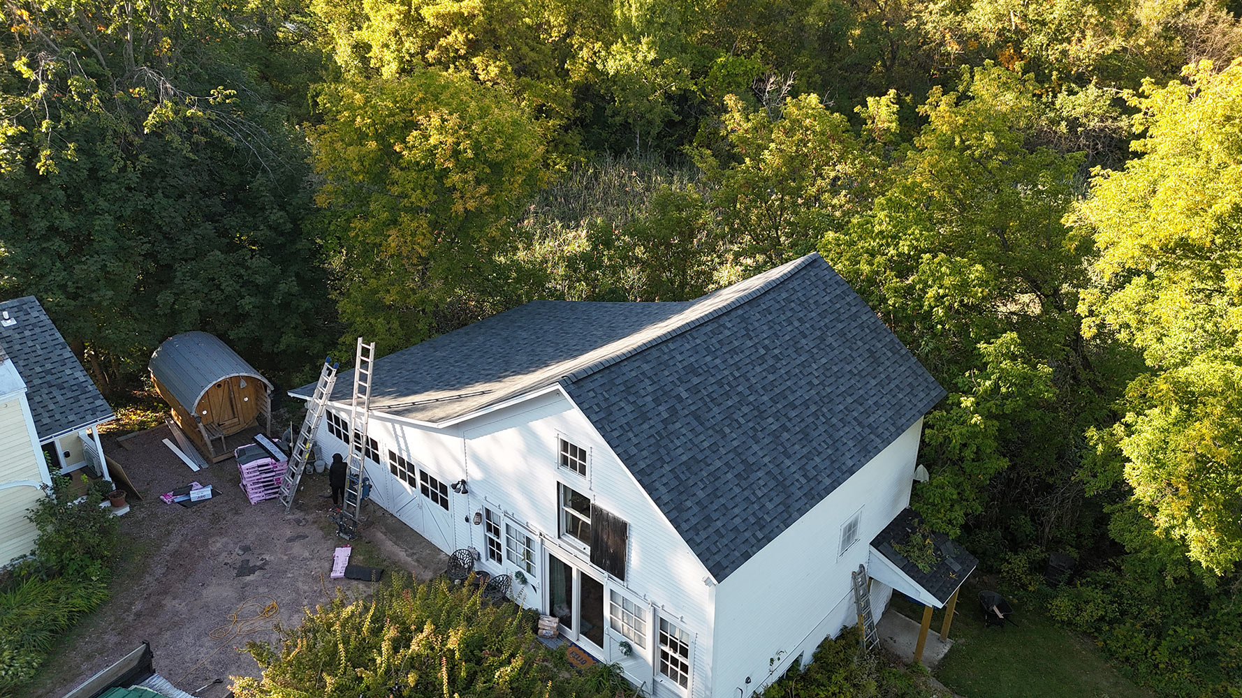 Completed charcoal shingle replacement on white Vermont farmhouse in Williston — golden hour aerial view