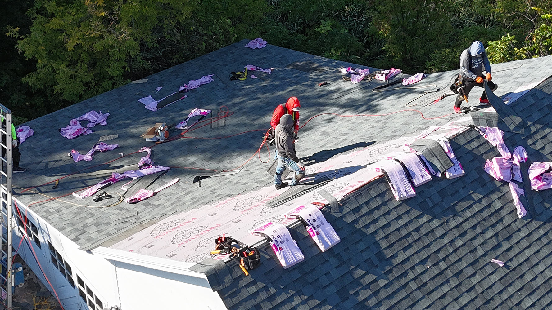 Close-up aerial of roofing crew installing charcoal architectural shingles on Williston Vermont farmhouse
