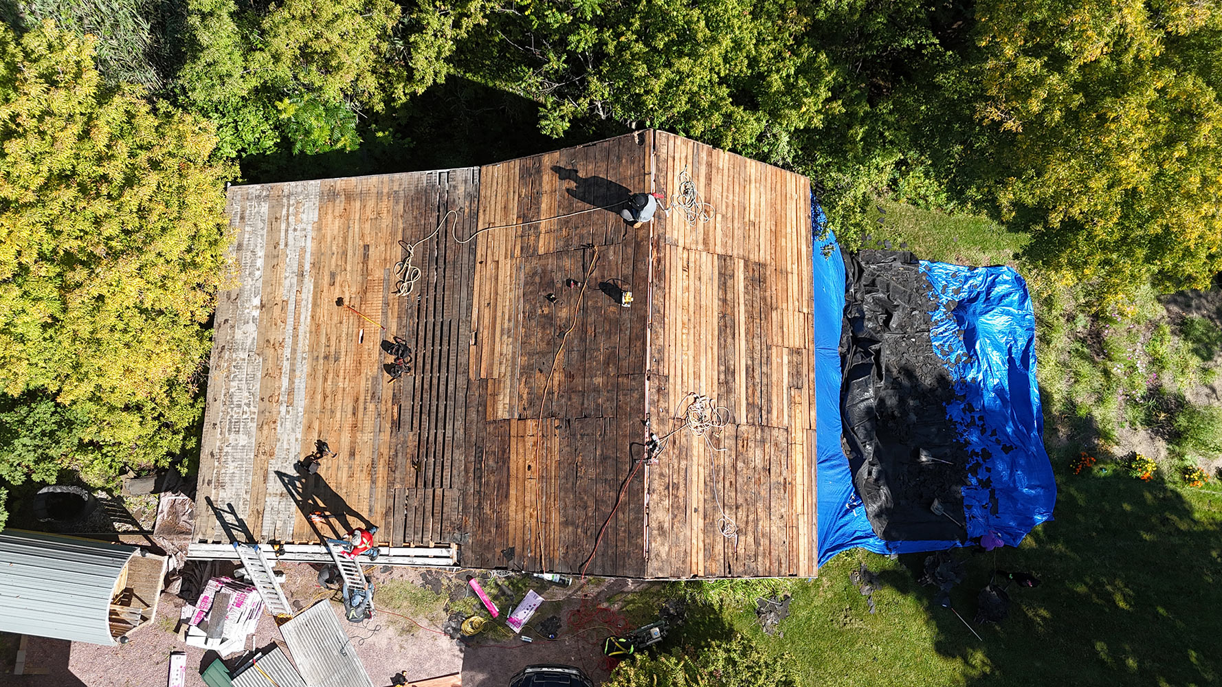 Overhead drone view of completely stripped roof deck on Williston Vermont farmhouse — original wood plank sheathing visible